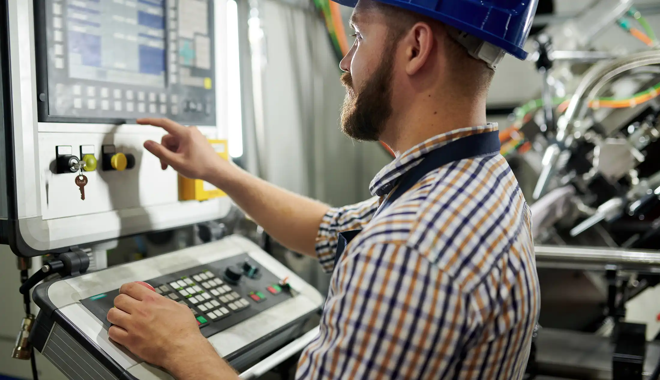 Portrait of machine operator wearing hardhat standing at control panel