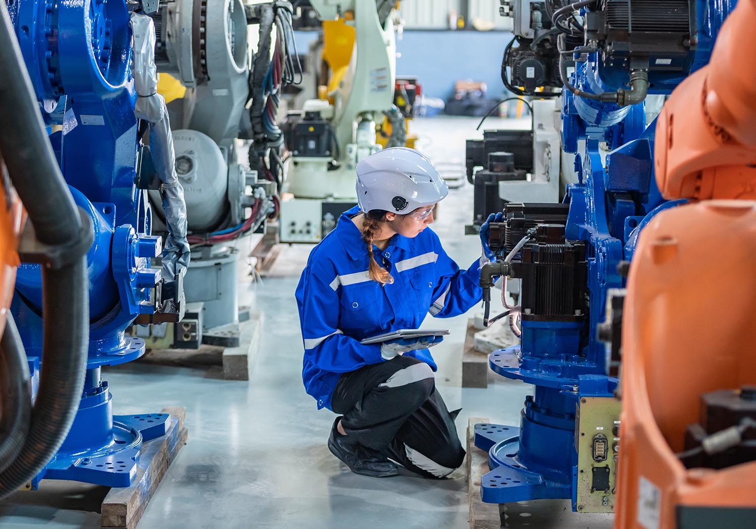 woman engineer in uniform helmet inspection check control heavy machine robot arm construction installation in industrial factory. technician worker check for repair maintenance electronic operation
