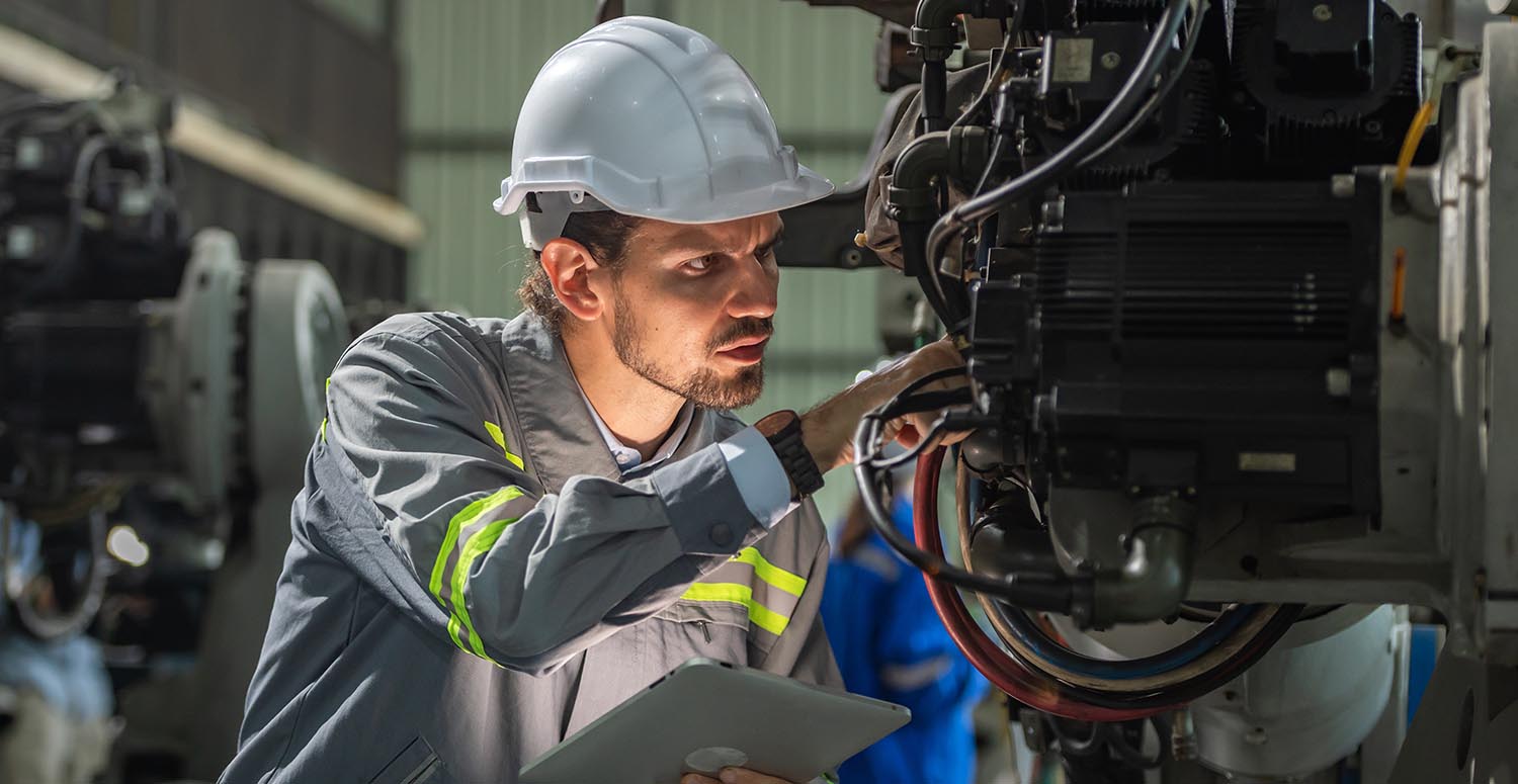 male automation engineer in uniform helmet safety inspection check control heavy machine robot arm system in industrial factory. technician worker check for repair factory machine