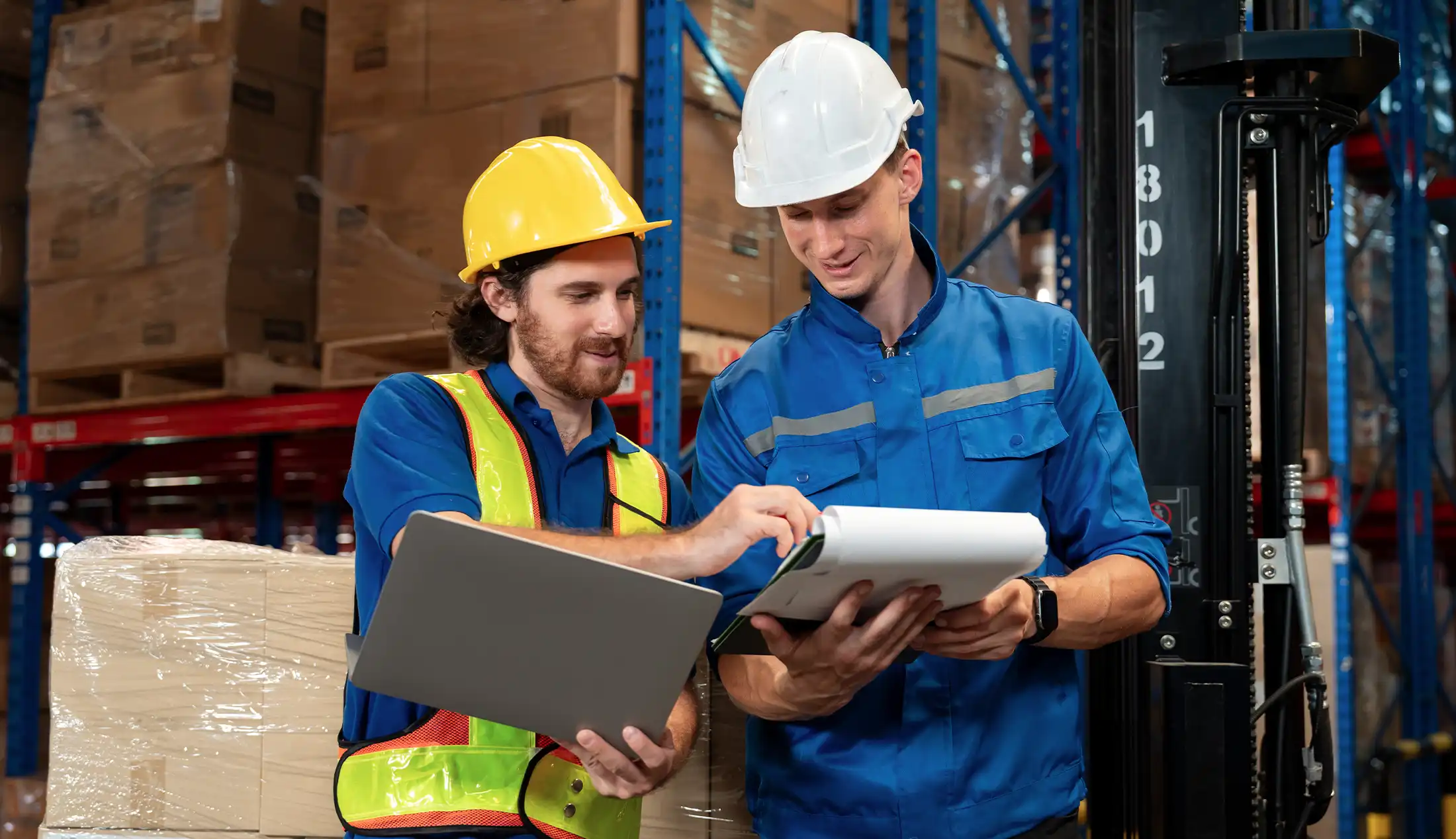 Male warehouse staff and supervisor reviewing stock